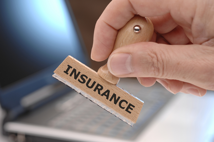 Concept photo about business insurance showing a hand holding a rubber stamp