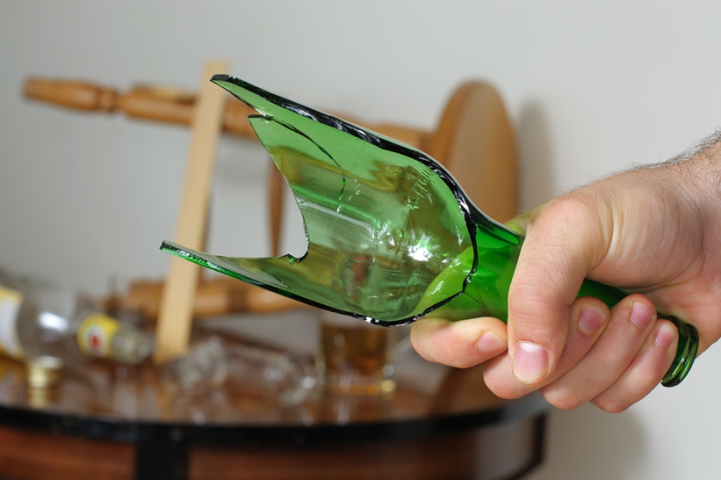 A broken bottle being used as a weapon by an intoxicated individual