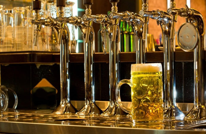 A row of beer taps and a mug of beer in a bar, pub, or tavern