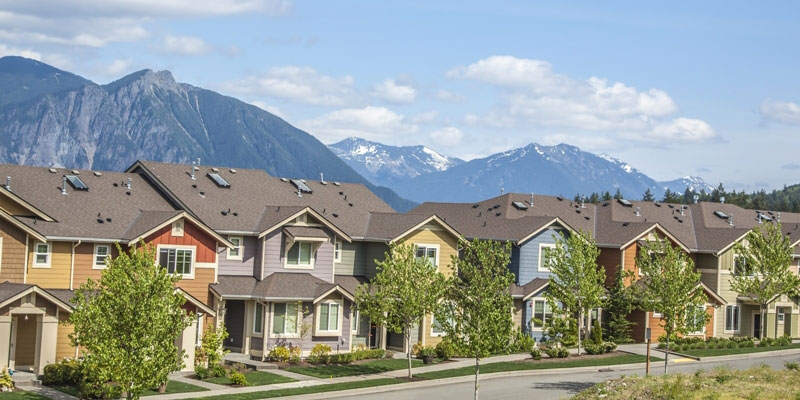 A row of duplex houses with a mountain range in the background