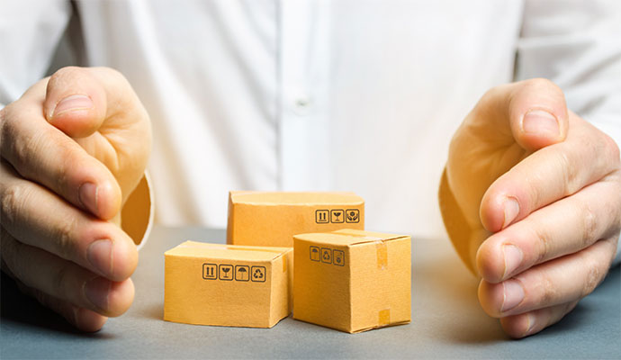 Hands protectively surrounding small cardboard shipping boxes