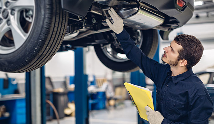 Mechanic inspecting vehicle in auto repair shop Mechanic inspecting vehicle in auto repair shop