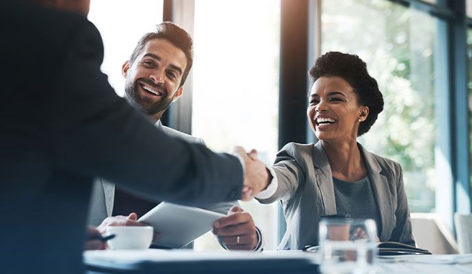 Smiling business professionals shaking hands across a table during a meeting